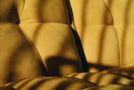 A yellow upholstered sofa with a textured fabric.