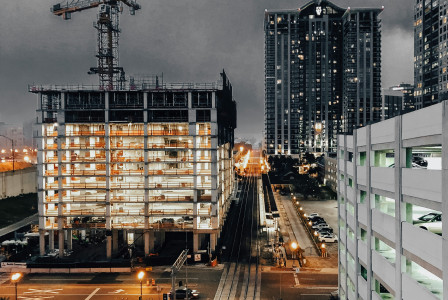 The picture presents a high-rise building under construction with cranes overhead.