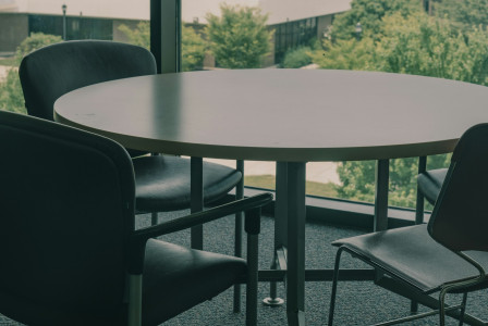 The photo presents a meeting table with chairs.