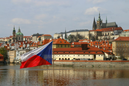 The photo presents the Czech flag with Prague in the background.