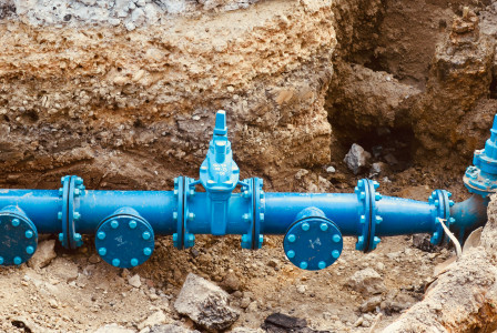 The image shows a newly installed water pipeline within an excavation trench, illustrating the modernisation of underground water distribution infrastructure.