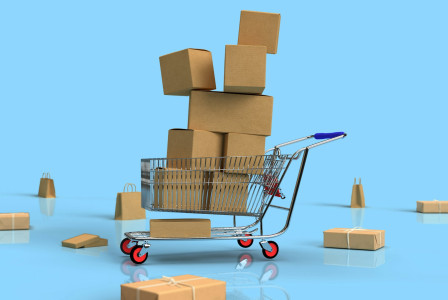 The photo presents a shopping cart filled with cardboard boxes.