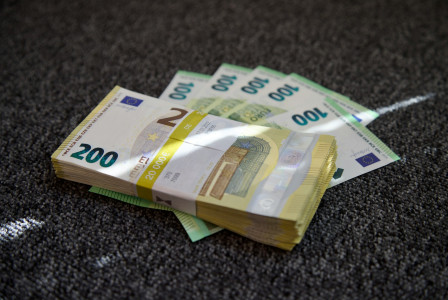 The photo presents stacks of euro banknotes.