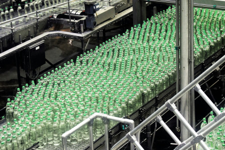 The photo presents plastic bottles on a production line.