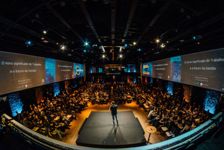 The photo presents a speaker addressing a conference audience.