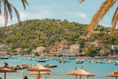 The photo shows a coastal town with boats and green hills.