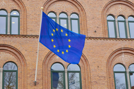 An European flag flying in front of a brick building.