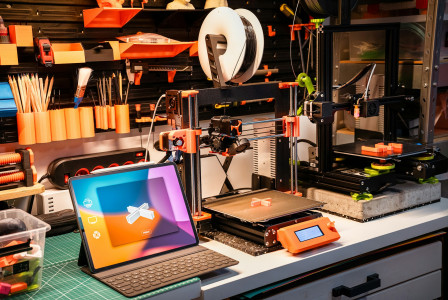 The photo presents 3D printers in a workshop.