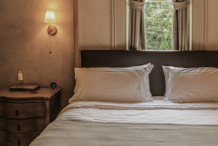 The photo shows a neatly arranged hotel bed and bedside table.