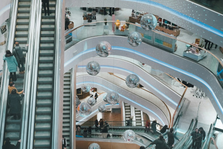 The photo presents people using escalators inside a shopping centre.