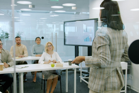 Woman presenting to an attentive audience in a modern office