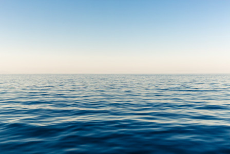 The photo presents a calm blue sea with gentle ripples stretching to the horizon beneath a clear sky.
