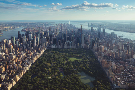 Aerial view of Central Park in New York City, surrounded by Manhattan's densely packed buildings and skyscrapers. 