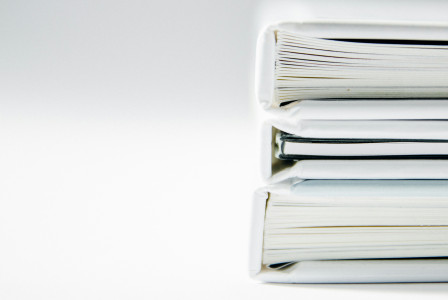 A stack of thick folders on a white surface.