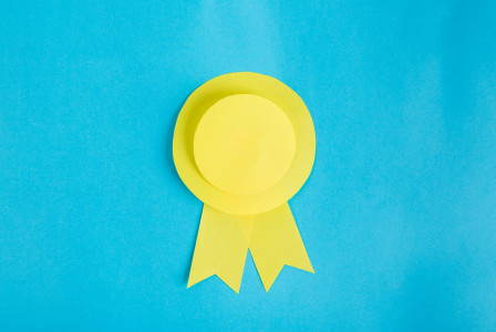 The photo presents a yellow award ribbon on a blue background.