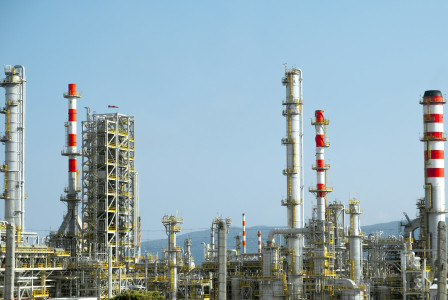 The photo presents an industrial refinery during the day.