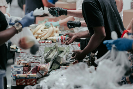 The photo presents volunteers sorting and packing donated food.