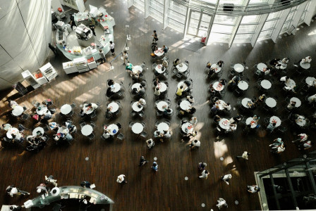 People in a building with a white and black tables and chairs.