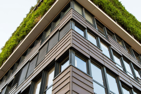 This picture shows a modern multi-story building photographed from a low-angle perspective, emphasizing its height and architectural design.
