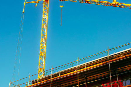 This picture shows an active construction site viewed from a low angle against a clear blue sky.