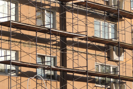 The picture shows the exterior façade of a multi-storey building undergoing renovation or maintenance work.