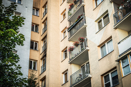 The picture shows the exterior of a multi-storey residential apartment building, viewed upward from a courtyard or the space between buildings.