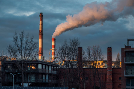 The picture shows an urban industrial setting, with factory infrastructure alongside other buildings and trees.