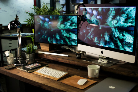 Colour photograph of two computer monitors turned on with the same wallpaper