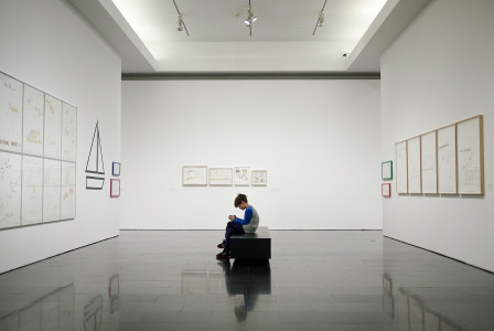 An illustrative photo of a man sitting near a painting in a museum