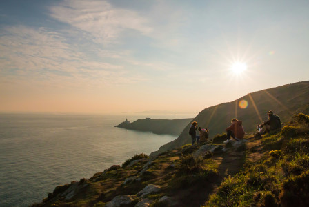Photo by Unsplash An illustrative photo of a group of people sitting on a grassy field near a body of water