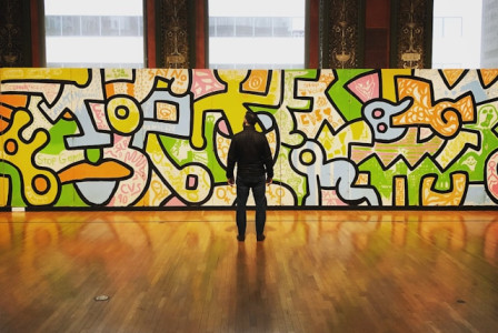 An illustrative photo of a man, standing in front of a vibrant, multicolored graffiti wall