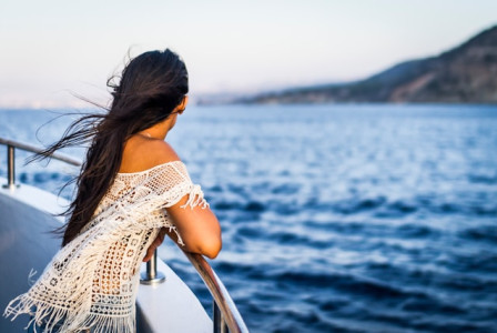 An illustrative photo of a woman on the boat watching the sea.