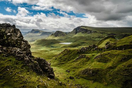 An illustrative photo of green grass on a mountain under a white cloudy sky