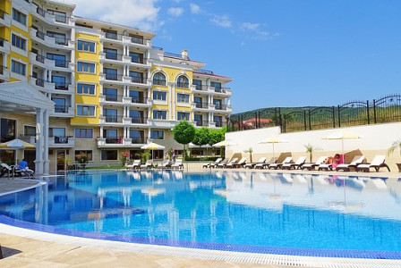An illustrative photo of a large outdoor swimming pool, overlooked by a building in Bulgaria