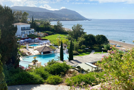 An illustrative photo of a coastal resort with white buildings and swimming pool 
