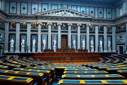 An illustrative photo of a large room filled with lots of wooden chairs
