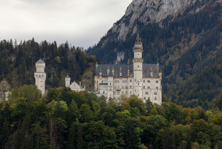 An illustrative photo of a castle perched on a hill with a mountain range in the background