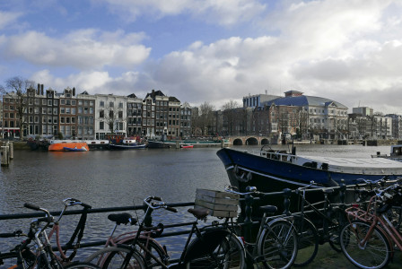 An illustrative photo of parked bikes along the river in Amsterdam