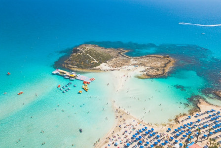 An illustrative photo of a beach scene with numerous blue umbrellas in Cyprus.