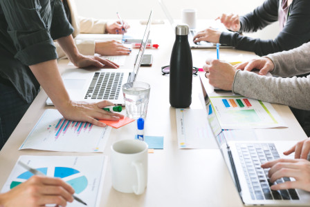 An illustrative photo of hands on desk during a meeting