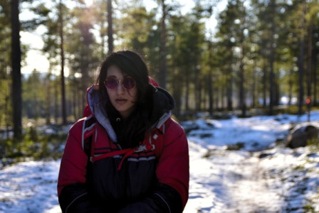 An illustrative photo of a woman in a jacket standing in a snowy landscape