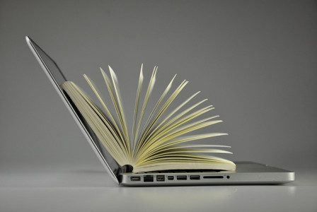 An illustrative photo of a laptop and a book placed side by side, symbolizing the blend of digital and traditional sources of information