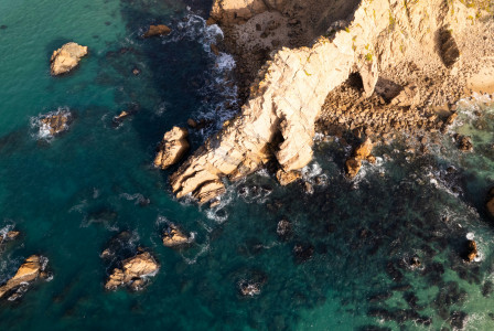 An illustrative photo of an aerial view of a rocky coastline with blue water