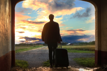 An illustrative photo of a man holding luggage, ready for his journey