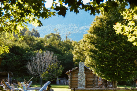 An illustrative photo of brown wooden fence near green trees in the mountains.