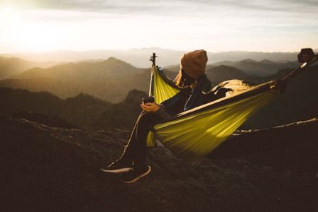 An illustrative photo of a woman sitting in hammock above mountains