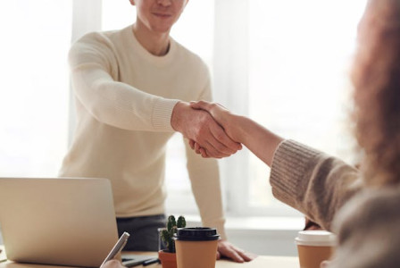 An illustrative photo of a man and woman engage in a conversation while seated at a table