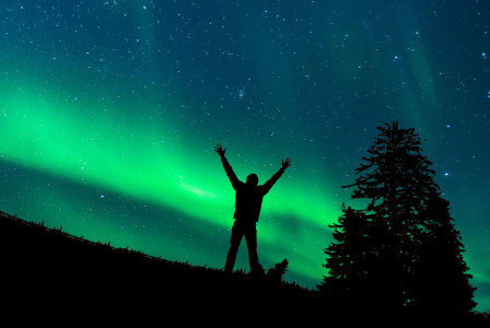 An illustrative photo of man standing on grass under starry night