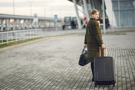 Photo by Unsplash An illustrative photo of the back view of a businesswoman carrying baggage before a flight near an airport building