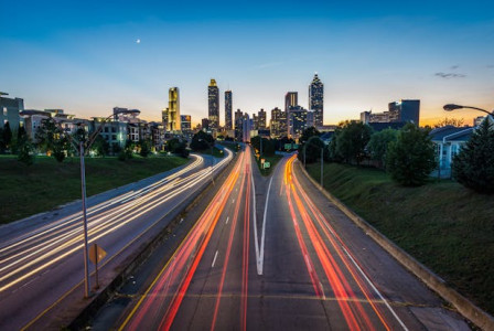 An illustrative photo of a cityscape at twilight with a clear sky and a visible crescent moon